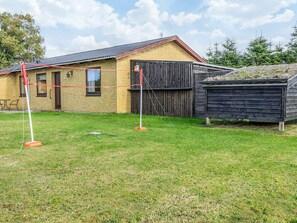 A building with a brick exterior, a wooden fence, and a grassy yard. - 4 Person Holiday Home in Bindslev (Bindslev)