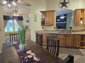 Una cocina con armarios de madera, lavavajillas integrado y un comedor con mesa y sillas.