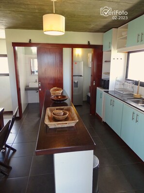 A modern kitchen with a central island, light blue cabinets, and a hanging light fixture.