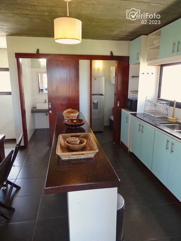 A modern kitchen with a central island, light blue cabinets, and a hanging light fixture.
