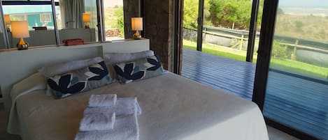 Un dormitorio con una cama grande, dos lámparas de noche, un espejo y vistas al exterior.