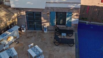 A two-story building with a terrace, outdoor seating, and a pool.