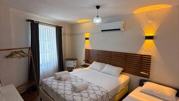 Una habitación de hotel con cama, escritorio, silla, armario y ventana con cortinas.