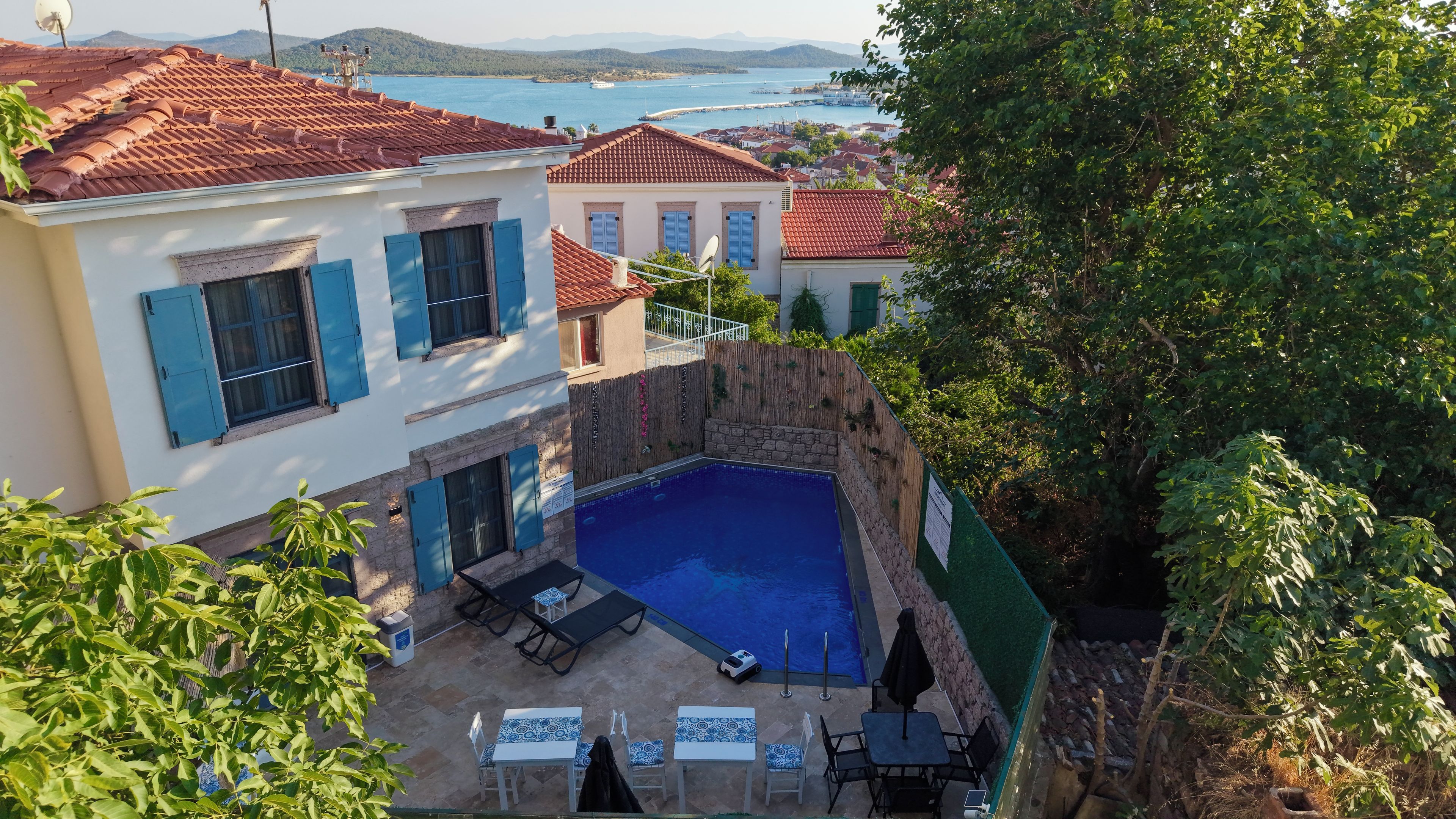 A villa with a swimming pool, outdoor seating, and a view of the sea.