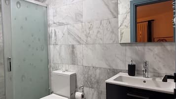 A bathroom with a toilet, shower, and vanity.