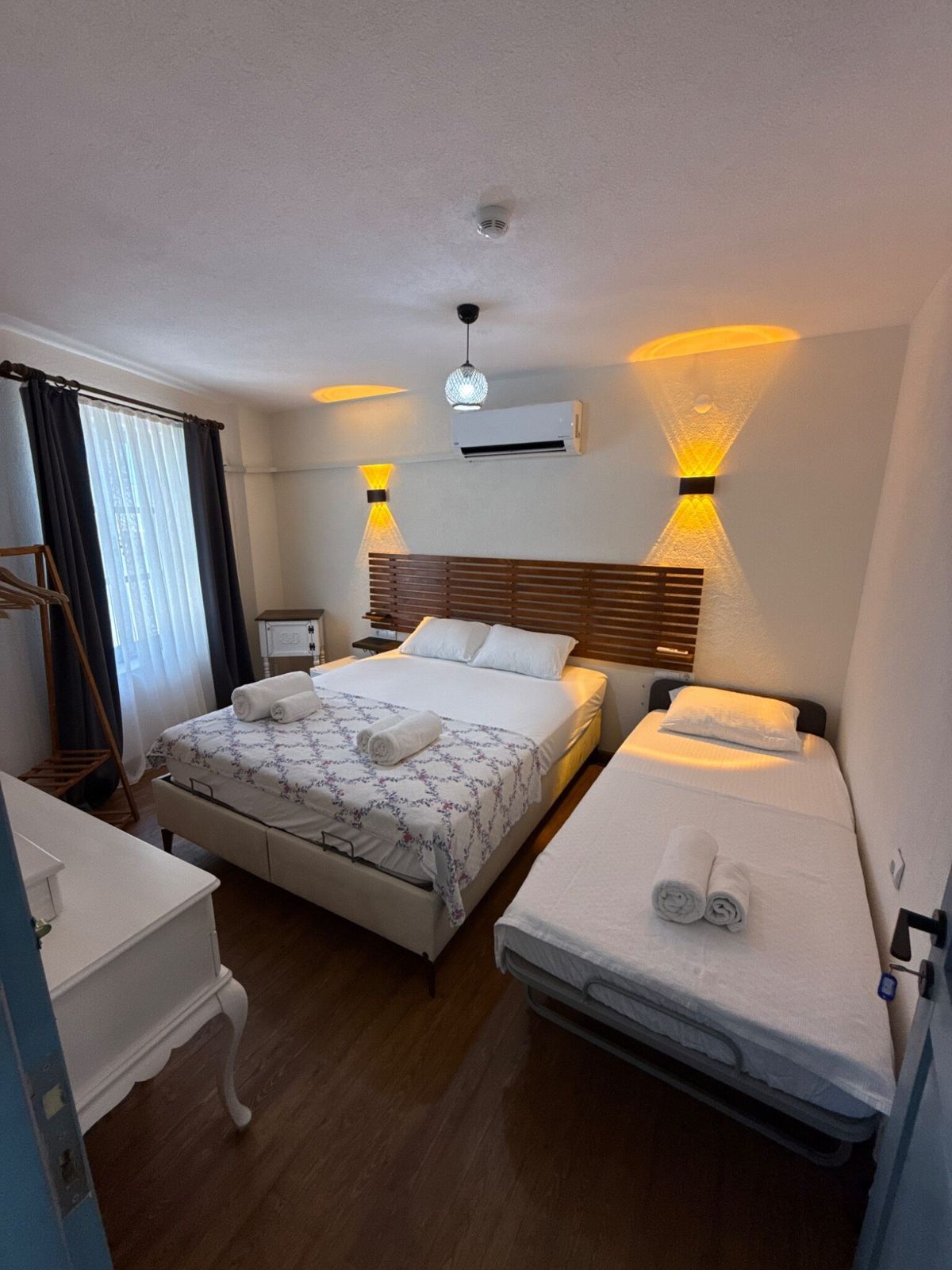 A hotel room with a large bed, a smaller bed, a desk, and a wardrobe.