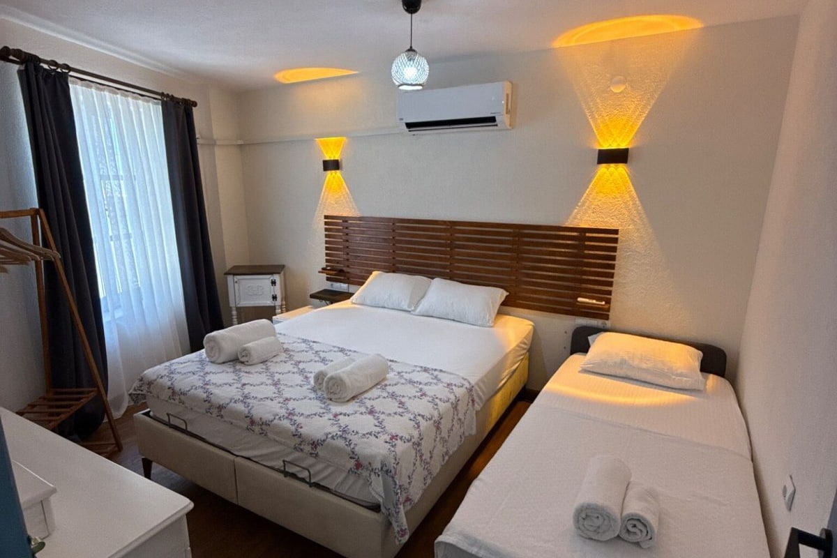 A hotel room with a large bed, a smaller bed, a desk, and a wardrobe.