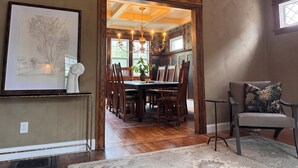 Un comedor con mesa de madera, sillas y una lámpara de araña.