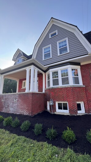 A two-story house with a gabled roof, red brick exterior, and white trim.