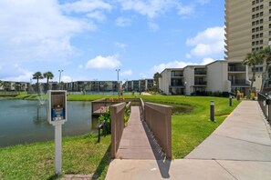 Um imóvel à beira-mar com uma ponte para pedestres, um espelho d'água e edifícios de apartamentos modernos.