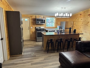 A compact kitchen with a central island, bar stools, and a refrigerator.