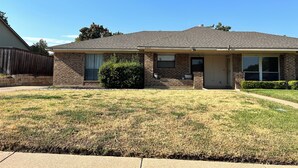 A single-story brick house with a front porch, a small front yard, and a clear blue sky. - Furnished 2BR + Office/Guest Room Near Texas Health HEB & DFW Airport (Bedford)