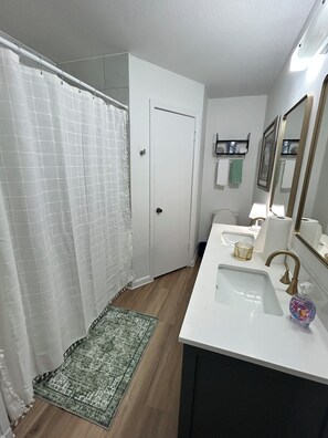 Ein Badezimmer mit Dusche, Waschbecken mit Spiegel und Toilette.