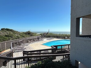 Ein Poolbereich mit Holzterrasse, Liegestühlen und Meerblick.