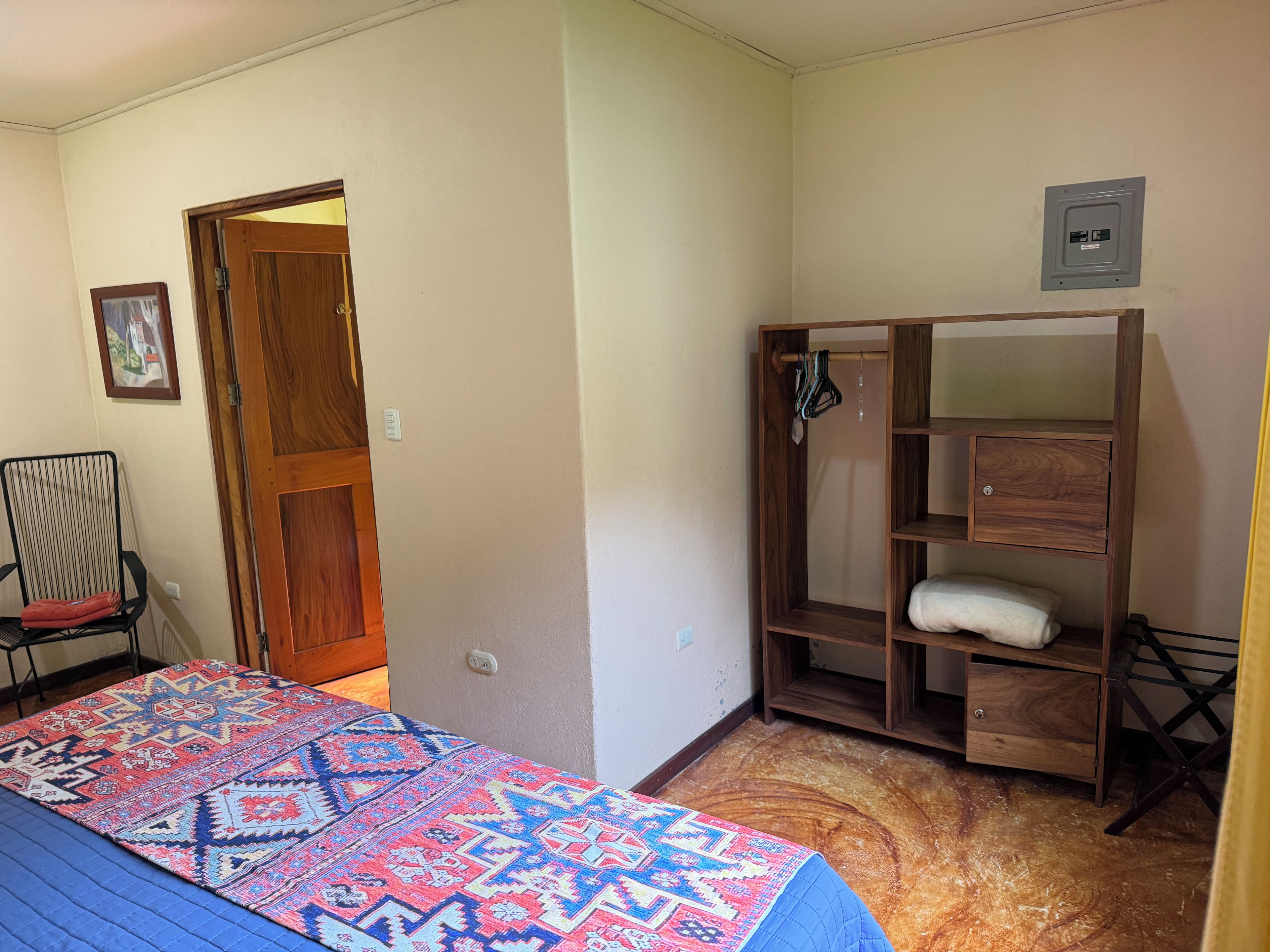Une chambre à coucher avec un lit, une armoire en bois, une chaise et une porte.