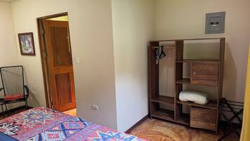 Une chambre à coucher avec un lit, une armoire en bois, une chaise et une porte.