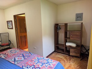 Un dormitorio con una cama, un armario de madera, una silla y una puerta.