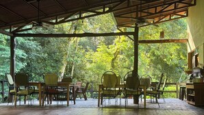 An outdoor covered patio with wooden flooring, metal chairs, and a table. - Rainforest Riverside Retreat Lake Arenal. Enjoy your family & friends getaway! (Tilaran)
