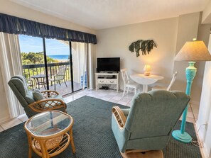 A room with a balcony, a television, a table with chairs, and a lamp. - Land's End Resort - King Suite w/ Peaceful Views | Perfect for Couples (Myrtle Beach)