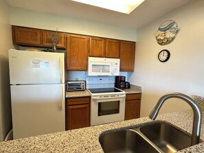 A kitchen with wooden cabinets, a microwave, a toaster, a coffee maker, and a sink. - Land's End Resort - King Suite w/ Peaceful Views | Perfect for Couples (Myrtle Beach)