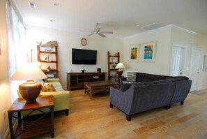 Una sala de estar con sofá, televisión, mesa de centro y lámpara.
