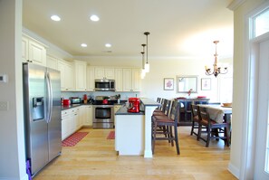 A modern kitchen with white cabinets, stainless steel appliances, and a central island with seating. - Land's End Resort - 2BR House | Gated Resort | Family Friendly (Myrtle Beach)