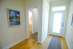 Ein Flur mit Holzboden, einer Tür mit Fenster und einem Gemälde an der Wand.