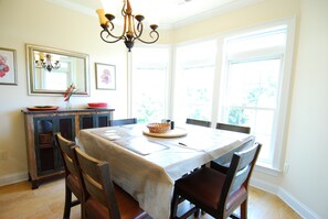 Un comedor con una mesa preparada para cuatro personas, un candelabro y un ventanal grande.
