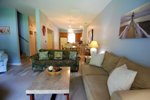 A living room with a sofa, a coffee table, and a dining area with a table and chairs. - Land's End Resort - 3BR Townhouse | Steps to Pool | Nature Views (Myrtle Beach)