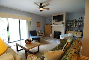 A living room with a sofa, a chair, a table, a fireplace, and a television mounted on the wall. - Land's End Resort - 3BR Townhouse | Steps to Pool | Nature Views (Myrtle Beach)