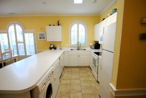 A kitchen with a large island, white cabinetry, a built-in oven, and a dishwasher. - Land's End Resort - Secluded 2BR Condo | Relaxing Getaway (Myrtle Beach)
