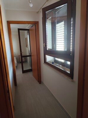 Ein Flur mit einer Holztür und einem Fenster mit Jalousien.