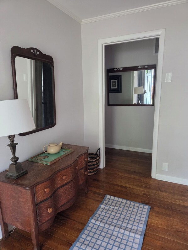 A room with a wooden dresser, a mirror, a lamp, and a blue checkered rug.