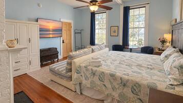 A bedroom with a bed, a ceiling fan, a fireplace, and a window with curtains.