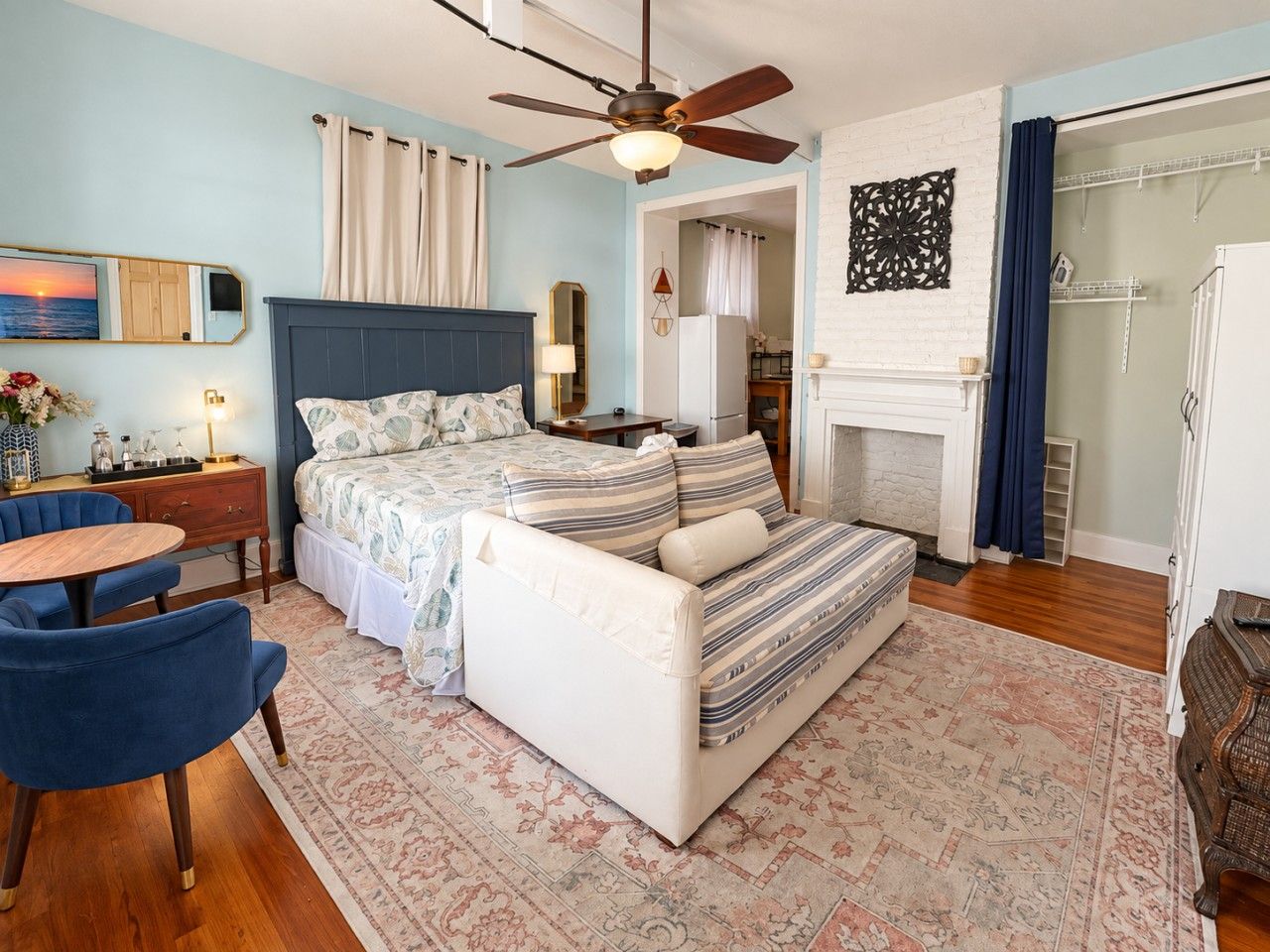 A bedroom with a bed, a sofa, a desk, and a chair.