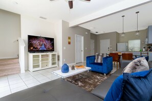 A living room with a flat-screen TV, a blue sofa, a coffee table, and a rug. - 3BR Bella Vida Townhome Pool & Mickey Room (Kissimmee)