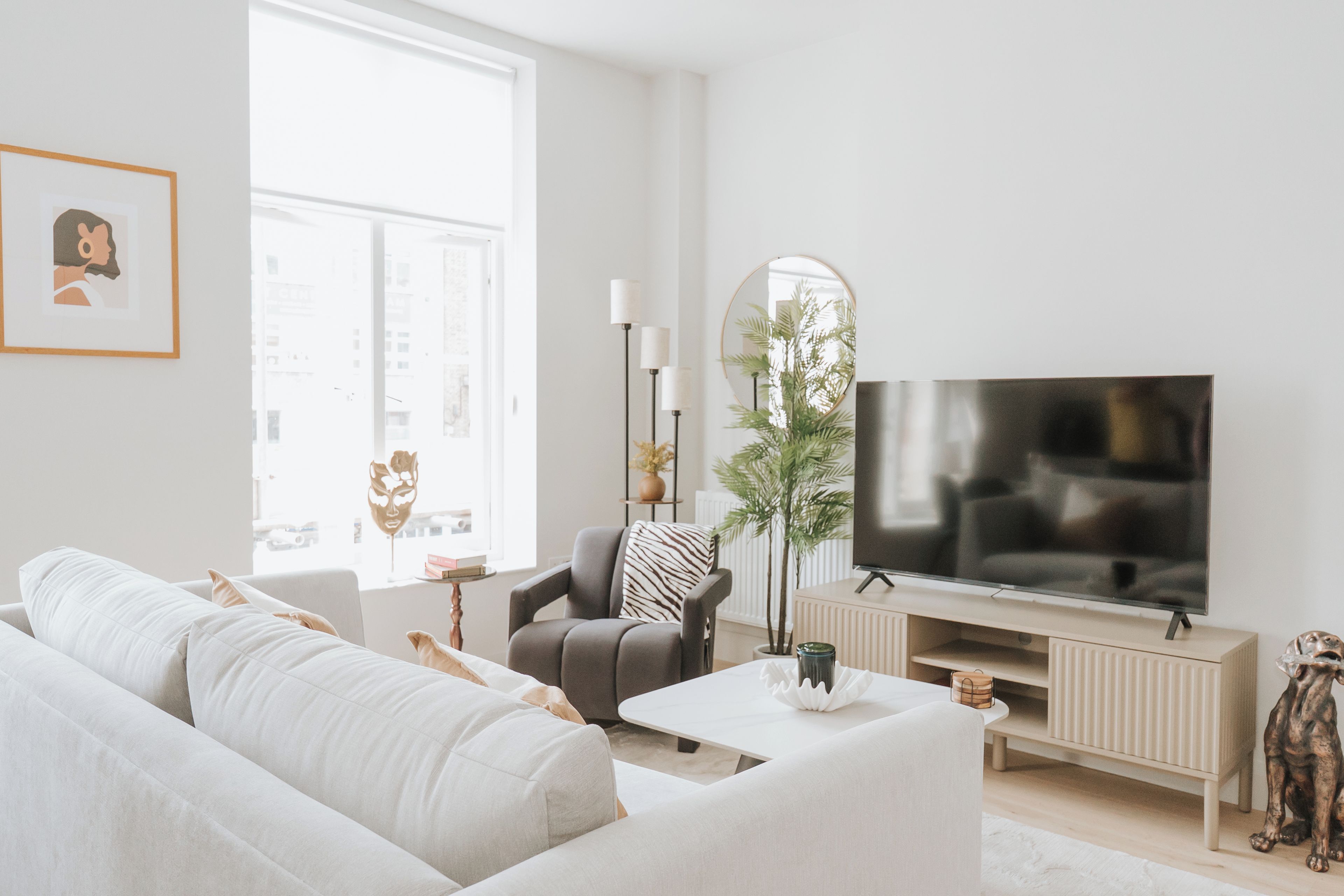 A modern living room with a sofa, armchair, coffee table, TV, and decorative items.