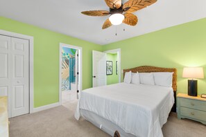 A bedroom with a bed, a nightstand, a lamp, a ceiling fan, and two doors. - Private Pool and Hot Tub — 5BR/4BA Beach House with Ocean Views in Surfside Beac (Surfside Beach)