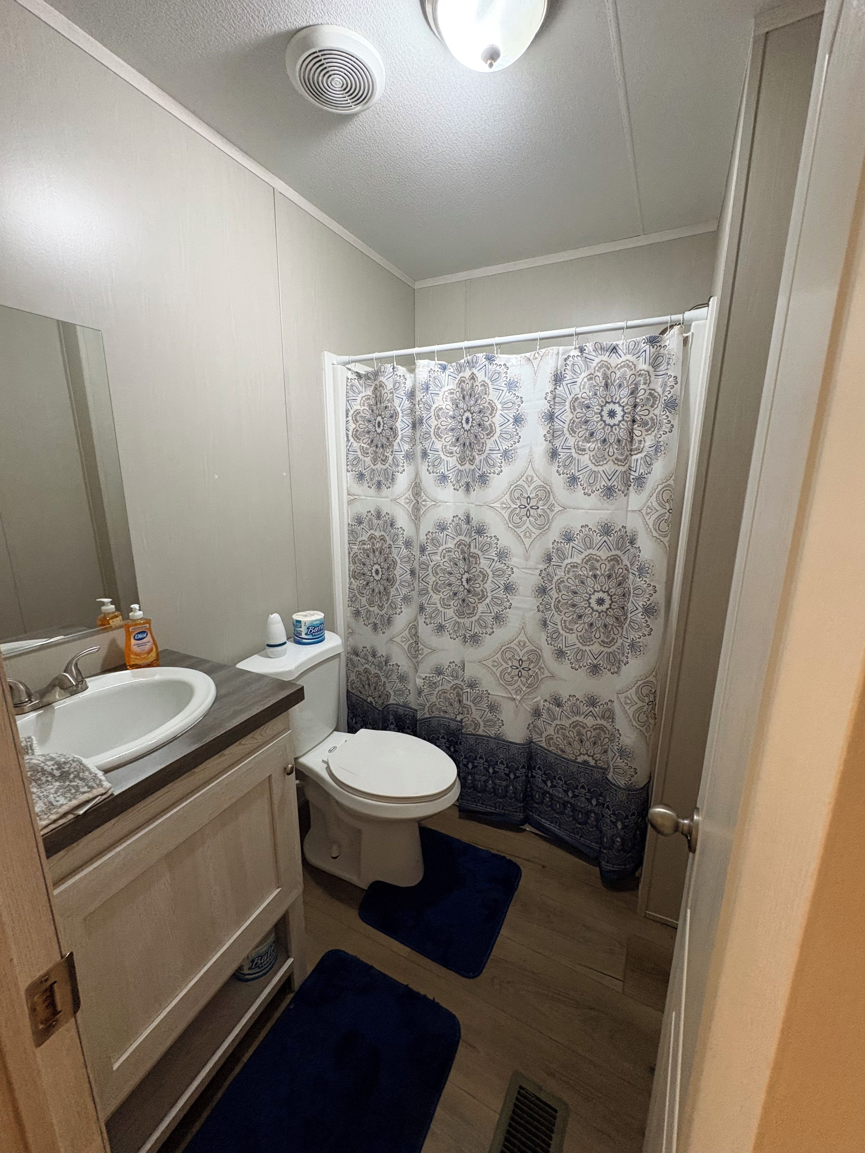 A bathroom with a white sink, toilet, and shower curtain with a geometric pattern.