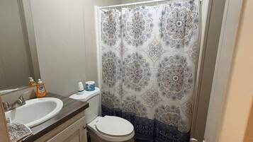 A bathroom with a white sink, toilet, and shower curtain with a geometric pattern.