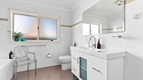 A modern bathroom with a toilet, sink, and mirror. - The Sanctuary House By Book Jervis Bay (Sanctuary Point)