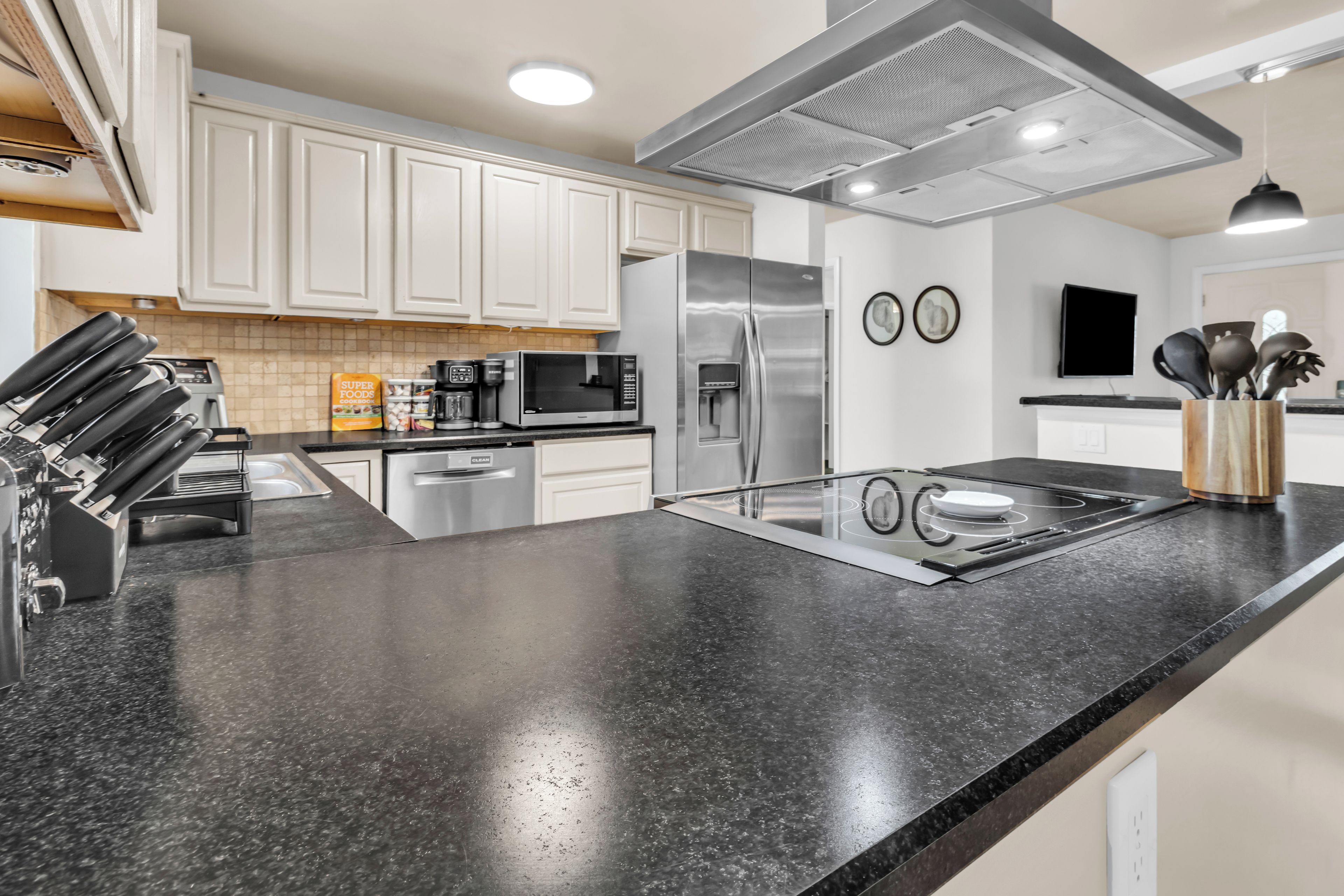 A modern kitchen with stainless steel appliances, a black granite countertop, and white cabinetry.