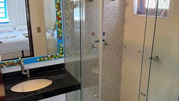Une salle de bain avec une douche à parois de verre, un lavabo avec un miroir et des toilettes.