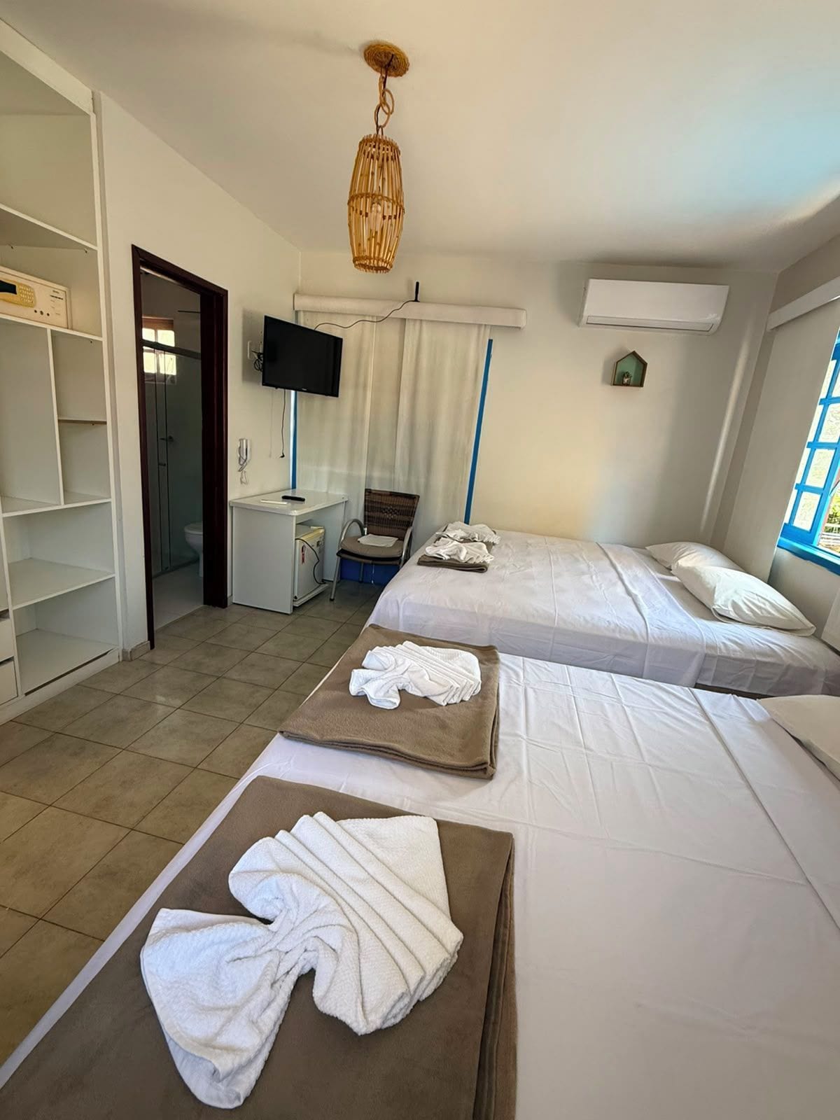 A hotel room with two beds, a television, a desk, and a bathroom visible through an open door.
