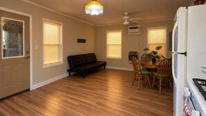 A compact living space with a kitchenette, a dining area with chairs and a table, a sofa, and a ceiling fan. - Ole Miss Football Game Rental! (Como)