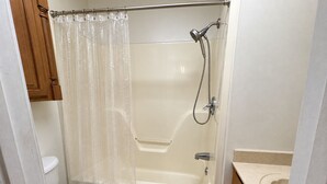 A bathroom with a bathtub, shower, toilet, and a sink. - Ole Miss Football Game Rental! (Como)