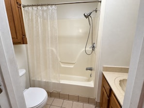 A bathroom with a bathtub, shower, toilet, and a sink. - Ole Miss Football Game Rental! (Como)