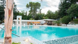 Una piscina al aire libre, sombrillas, sillones reclinables de piscina