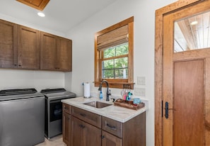 A compact kitchen with wooden cabinets, a built-in stove, a sink, and a window with a view of greenery.