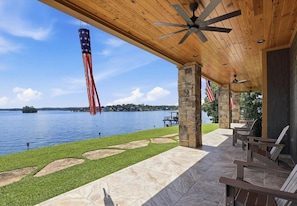 A covered patio with stone pillars, outdoor seating, and a view of a lake.